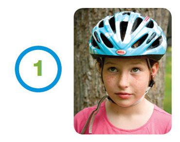 Young girl modeling the proper way to wear a bicycle helmet.