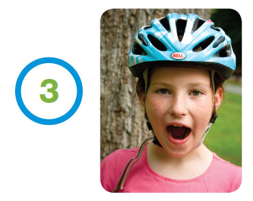 Young girl modeling the proper way to wear a bicycle helmet.